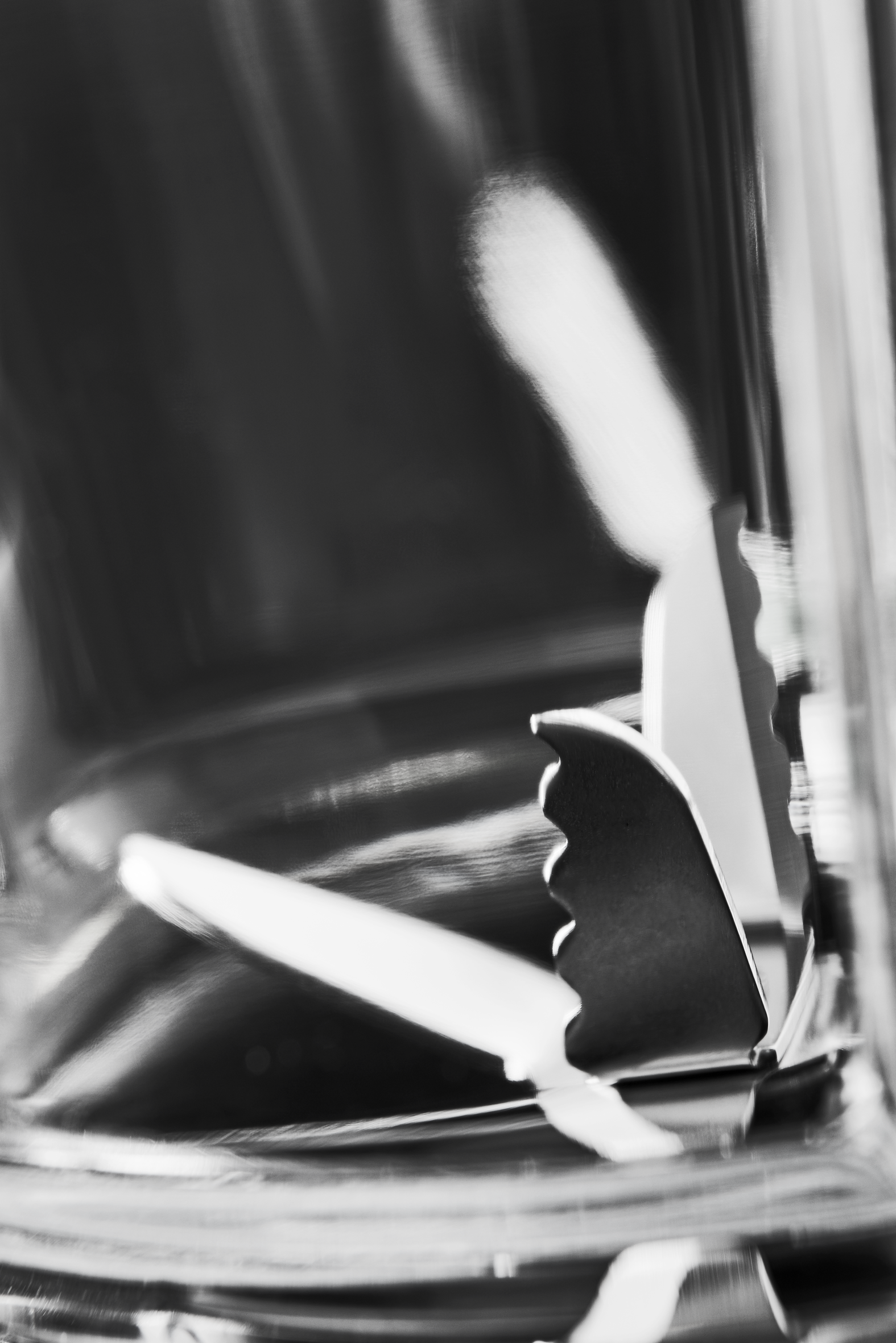 Close-up of serving tongs inside a glass. The tongs are silver and the glass is transparent.