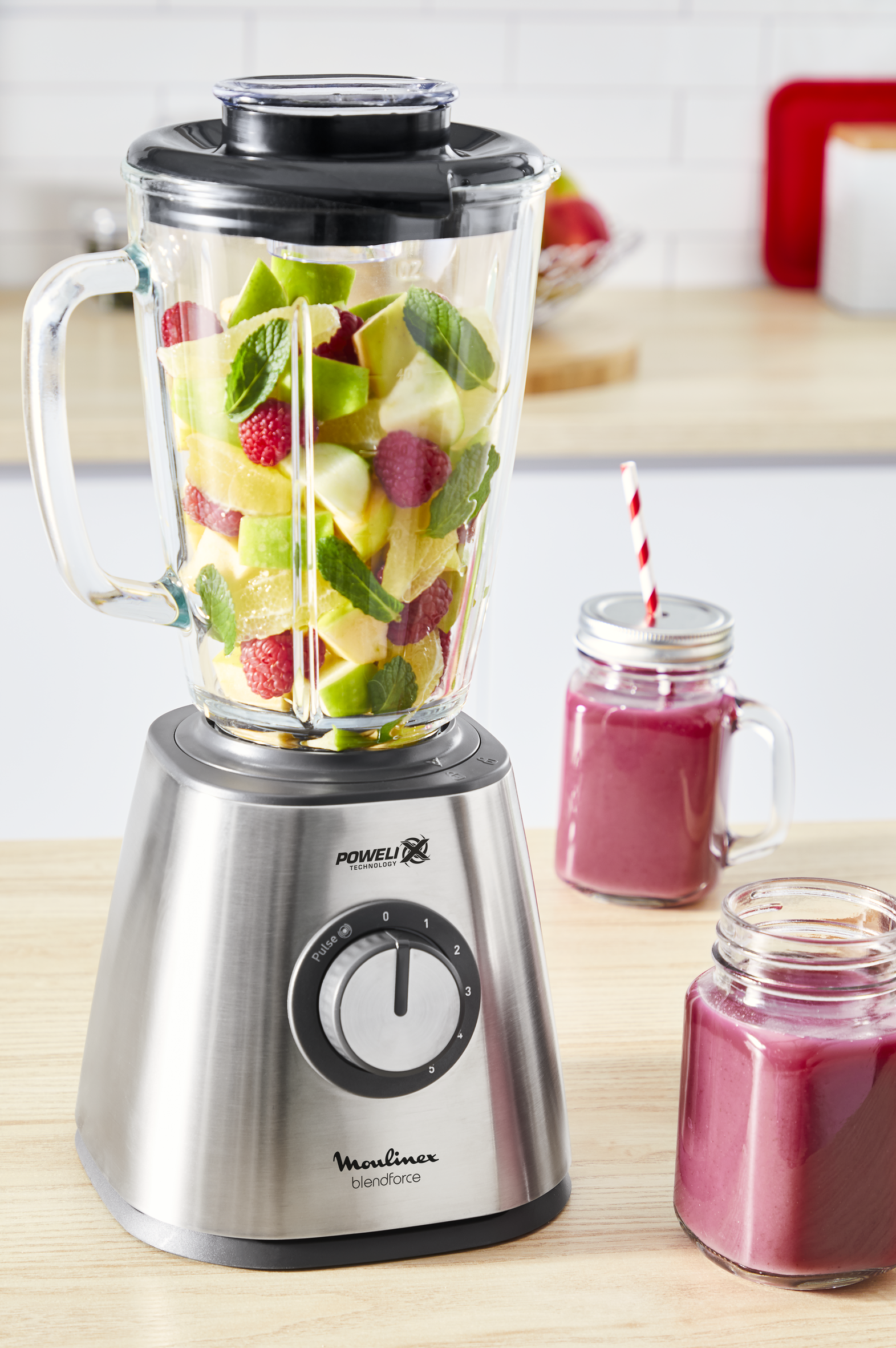Blender with fruits and a smoothie in a jar.