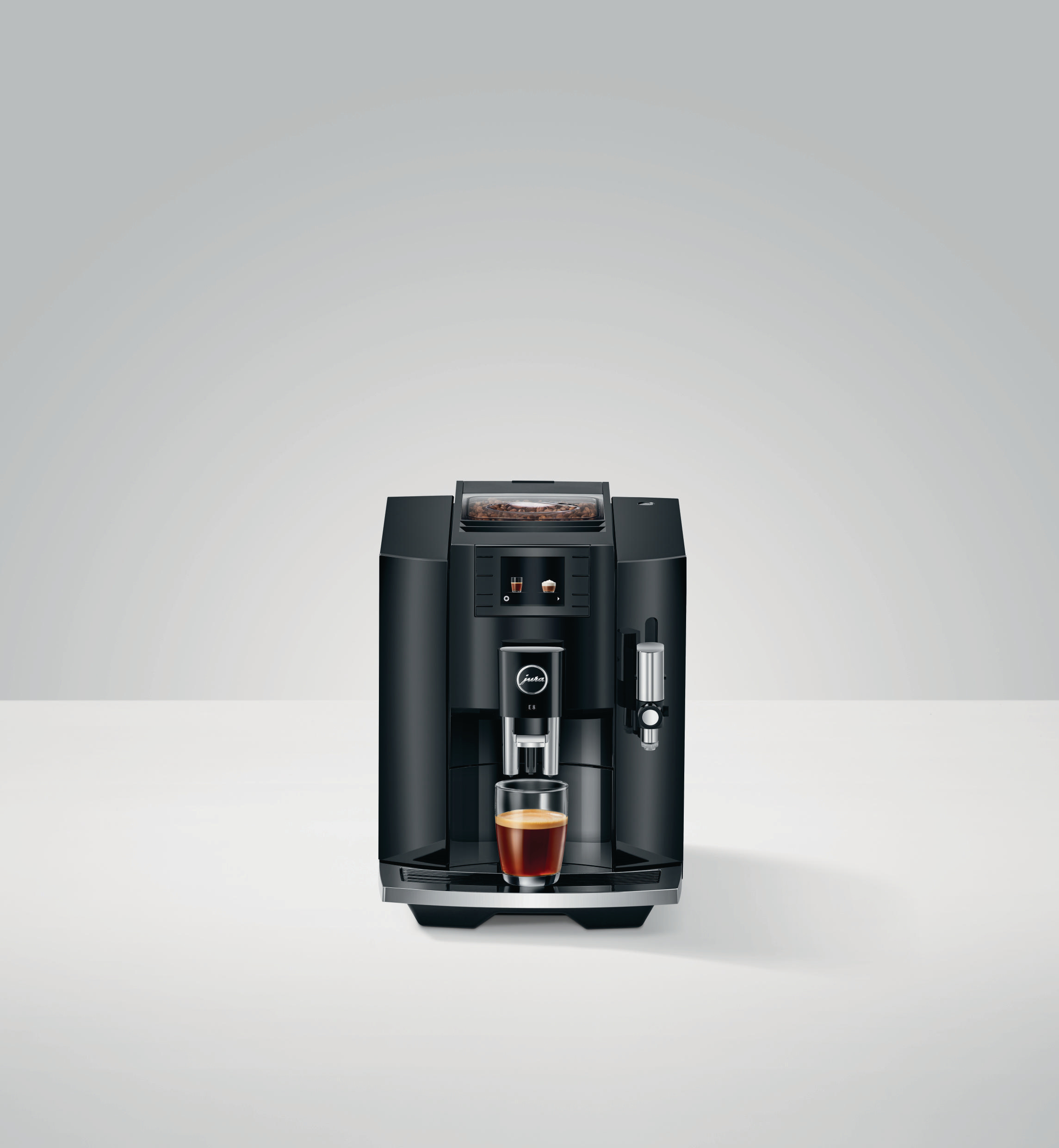 Eine schwarze Kaffeemaschine mit einem Glas Kaffee. Die Maschine hat einen Bildschirm und einen silbernen Ausguss.