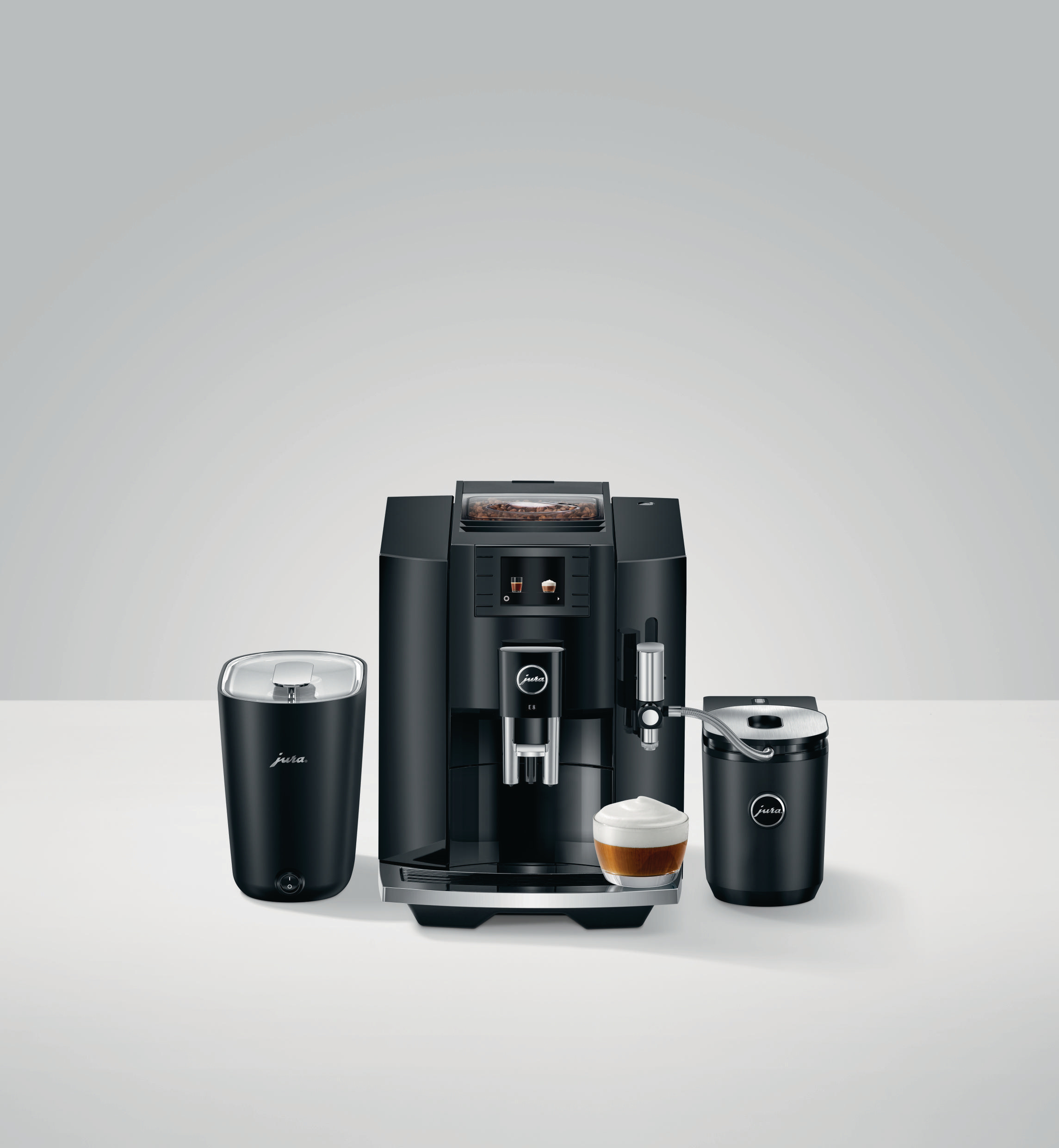 Schwarze Kaffeemaschine mit Zubehör. Eine Tasse Kaffee steht davor.