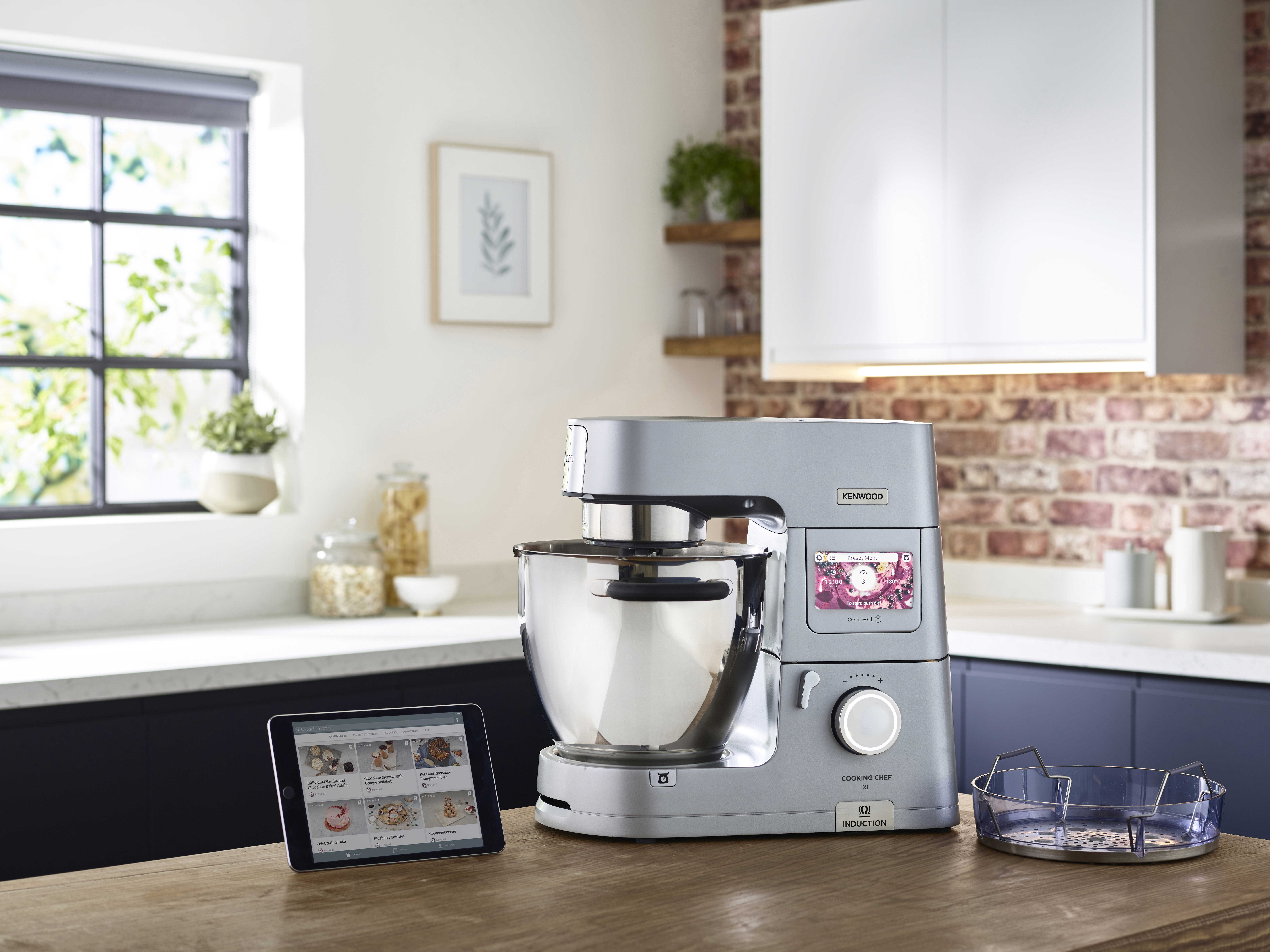 Graue Kenwood Cooking Chef Küchenmaschine mit Zubehör und Tablet.