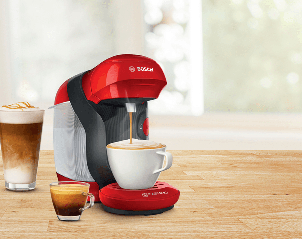 Eine rote Kaffeemaschine mit Kaffee und einem Glas Latte.