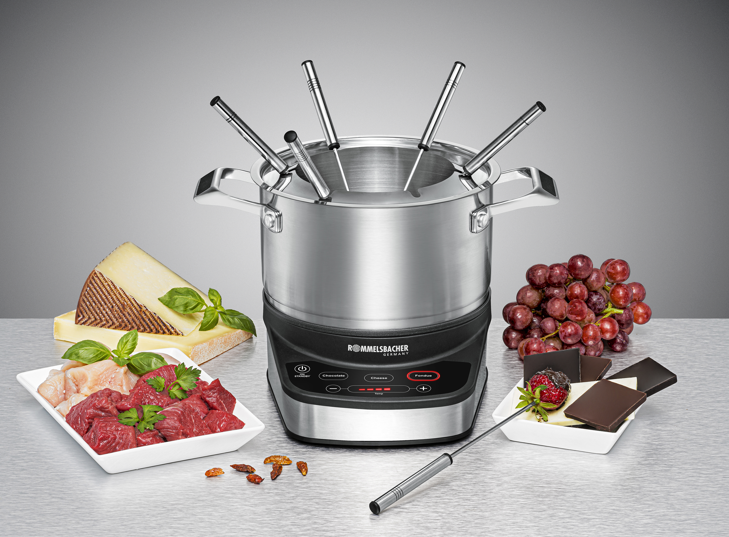 Ein Fondue-Set mit Fleisch, Käse und Trauben.