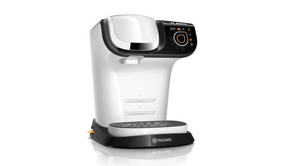 Weiß-schwarze Tassimo Kaffeemaschine mit einer Tasse auf dem Sockel, vor weißem Hintergrund.