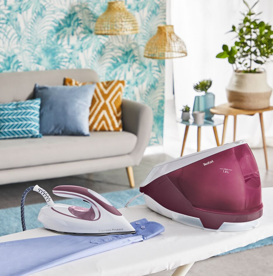 Ironing board with a white iron and a steam generator in a room.