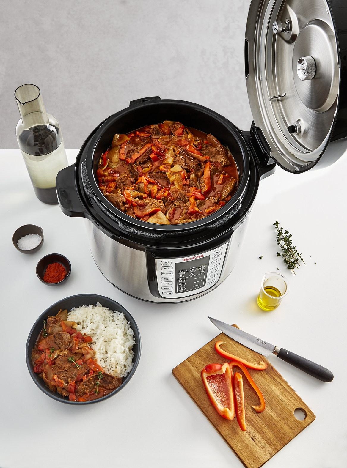 Open snelkookpan met stoofschotel en rijst. Ingrediënten: tomaten, paprika's, vlees, kruiden.