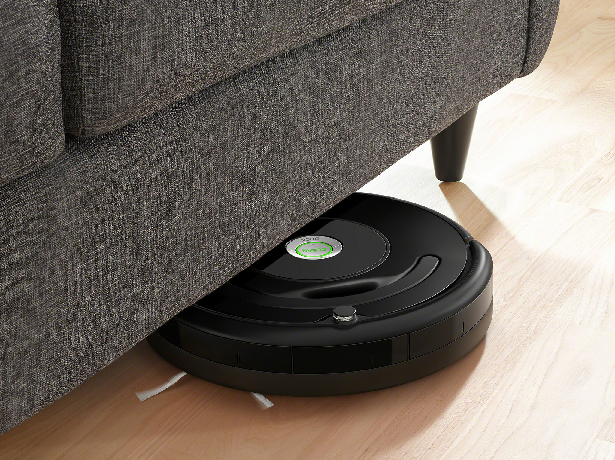 Roboter-Staubsauger unter einem Sofa. Demonstriert die Fähigkeit, unter Möbeln zu reinigen.