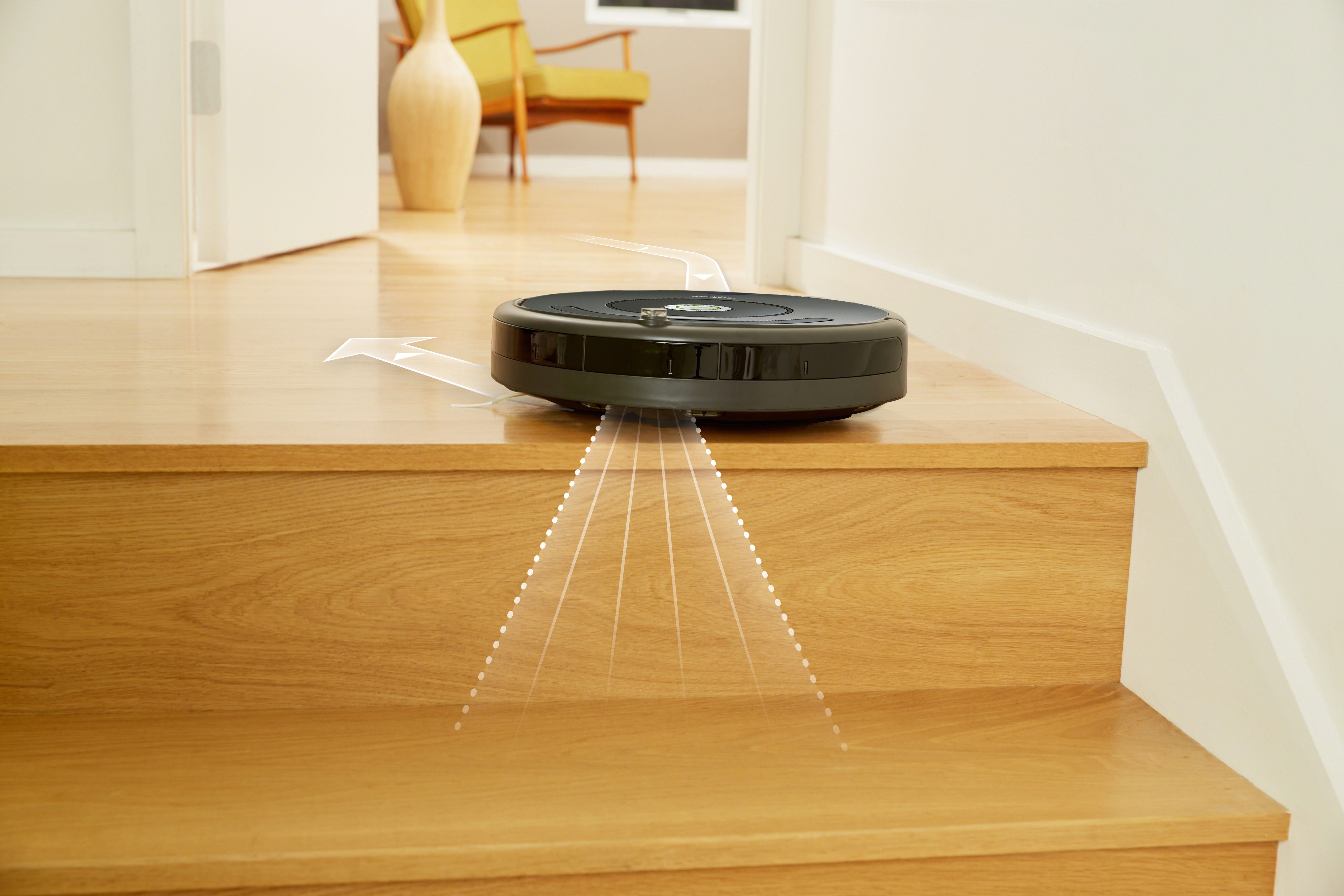 Schwarzer Roboter-Staubsauger auf Holzstufen. Er hat einen schwarzen Körper und steht kurz davor, in die untere Etage zu gehen.