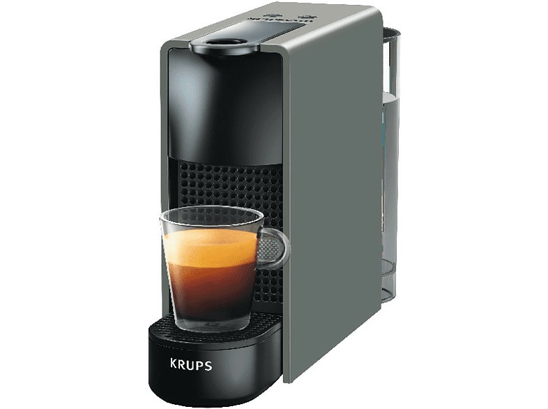 Una máquina de espresso Krups gris con un vaso de espresso y una base negra. Está sobre blanco.