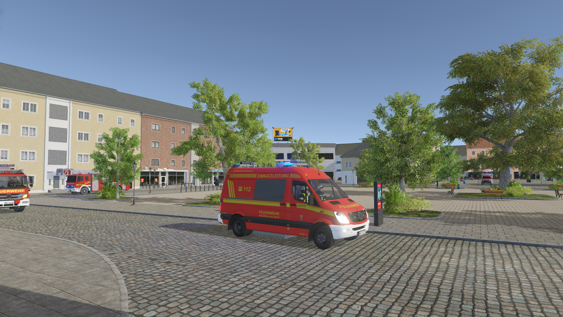 Stadtbild mit einem rot-weißen Feuerwehrauto, einem Feuerwehrwagen, Bäumen und Gebäuden.