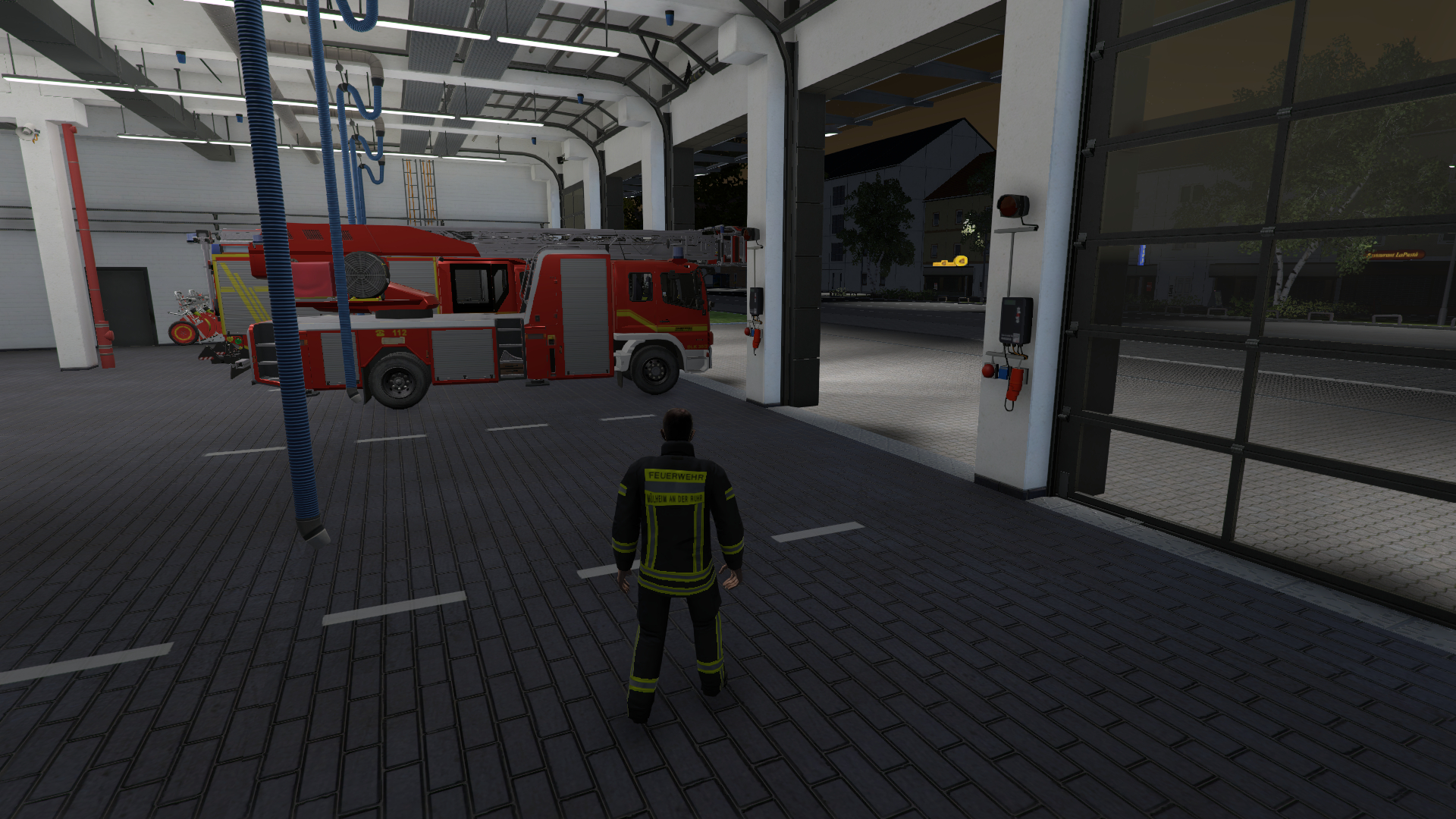 Ein Feuerwehrmann steht in einer Feuerwache. Im Hintergrund sind ein Feuerwehrauto und andere Geräte zu sehen.