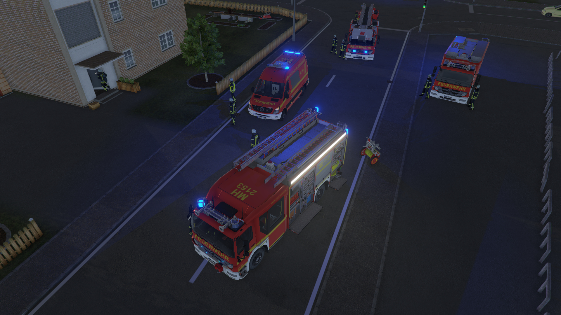 Feuerwehrfahrzeuge und Krankenwagen auf einer Straße mit Feuerwehrleuten. Gebäude sind im Hintergrund.