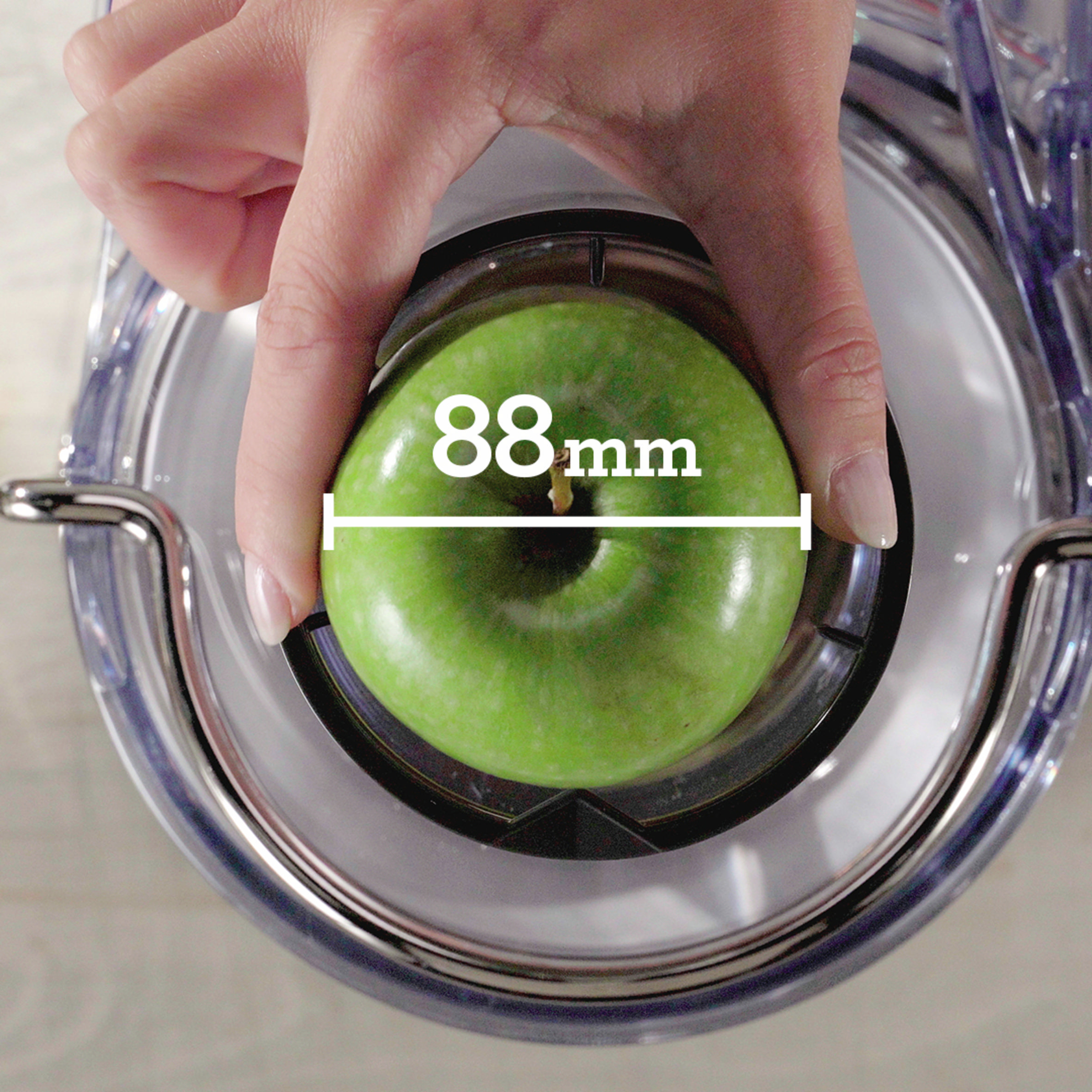 Ein Apfel wird mit einer weißen Linie von 88 mm gemessen. Der Apfel ist grün, in einem transparenten Behälter.