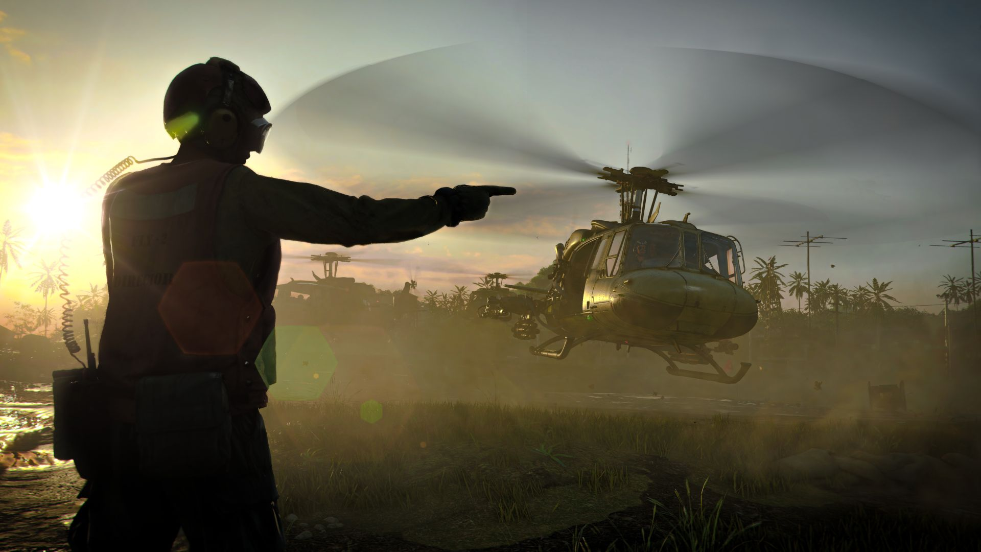 Soldado señalando un helicóptero en un campo. Puesta de sol al fondo, con otros helicópteros.