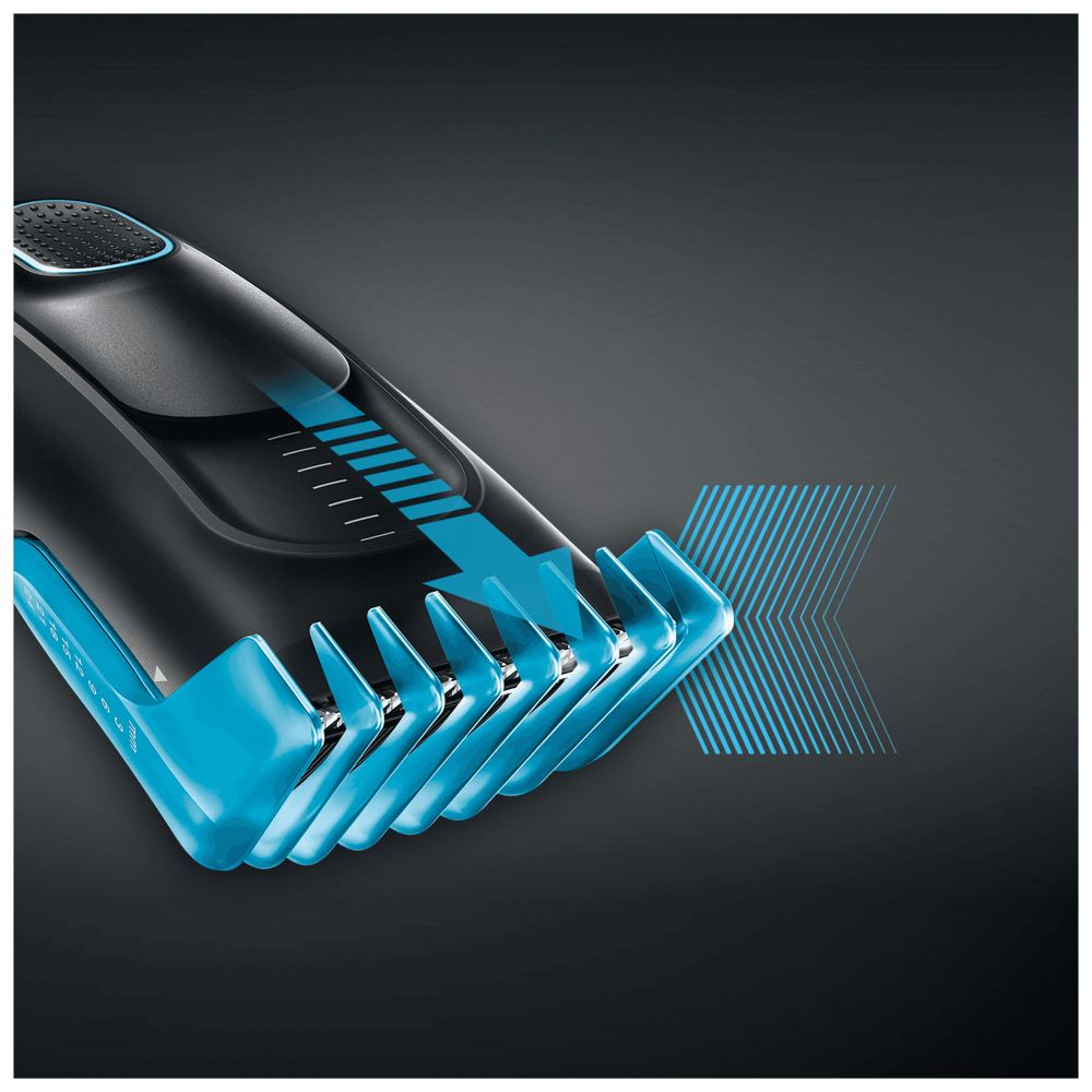 Primer plano de una cortadora de pelo azul y negro con ajustes numerados, sobre fondo oscuro.