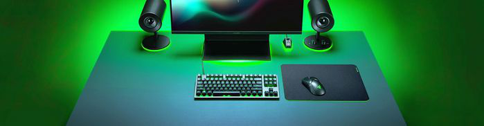 Une configuration de jeu éclairée en vert avec moniteur, enceintes, clavier et souris.
