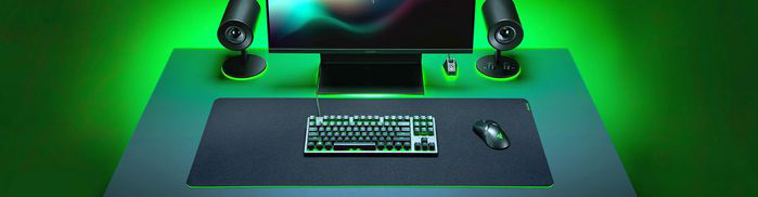 Configuration de jeu avec éclairage vert : moniteur, haut-parleurs, clavier, souris.