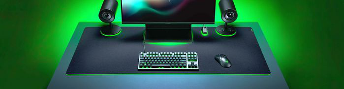 Configuration de jeu avec clavier, souris, haut-parleurs et moniteur, éclairage vert.