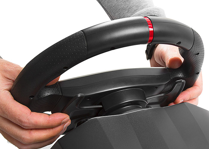 Kırmızı detaylara sahip siyah bir oyun direksiyonunu tutan eller. Beyaz zemin.