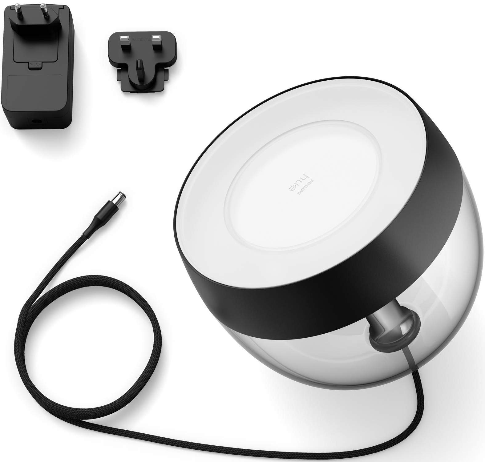 Une lampe blanche et noire avec une base transparente. Câbles et deux prises visibles.