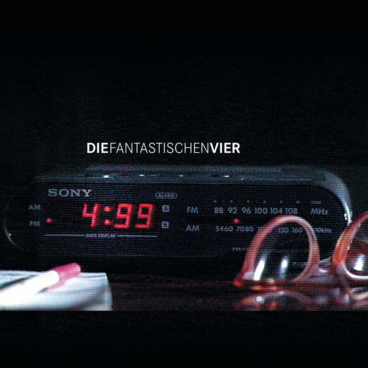 Ein alter Sony Wecker mit roter Anzeige 4:59, daneben eine Brille und ein Stift.