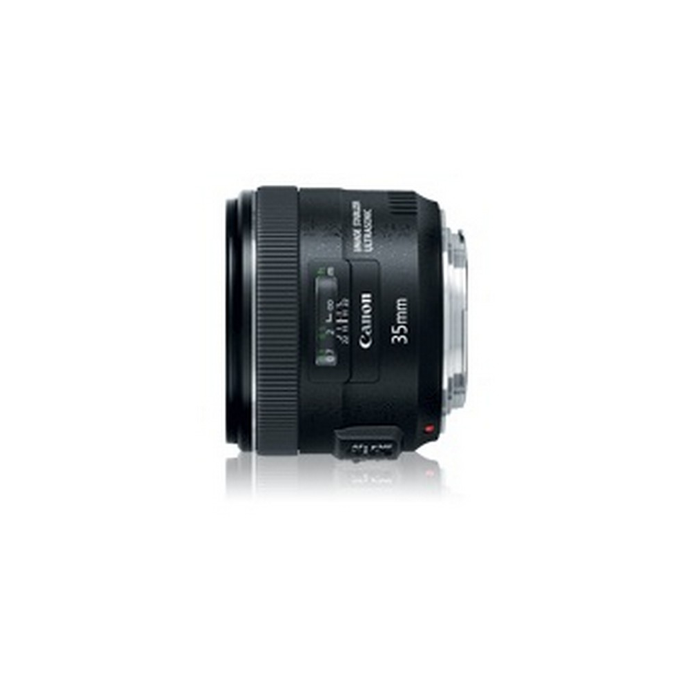 Lente Canon 35mm negro. Tiene un cuerpo negro y un anillo de enfoque. La lente está sobre un fondo blanco.