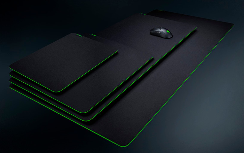 Four black Razer mouse pads of different sizes. A black mouse is on the largest pad.