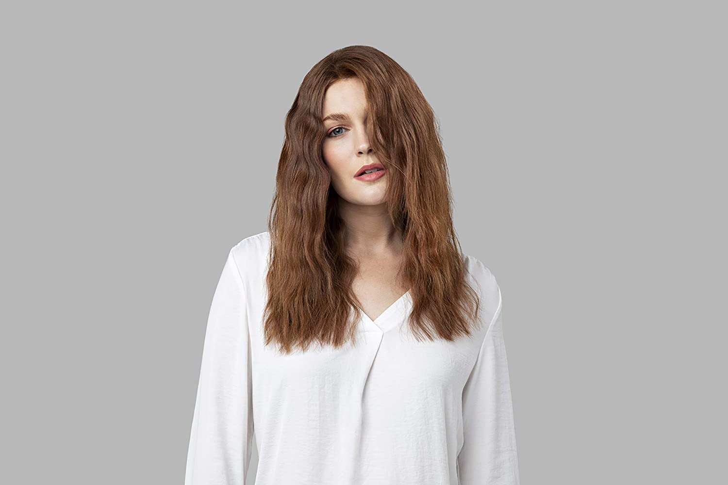 Eine Frau mit langen, welligen, roten Haaren, die in die Kamera schaut.