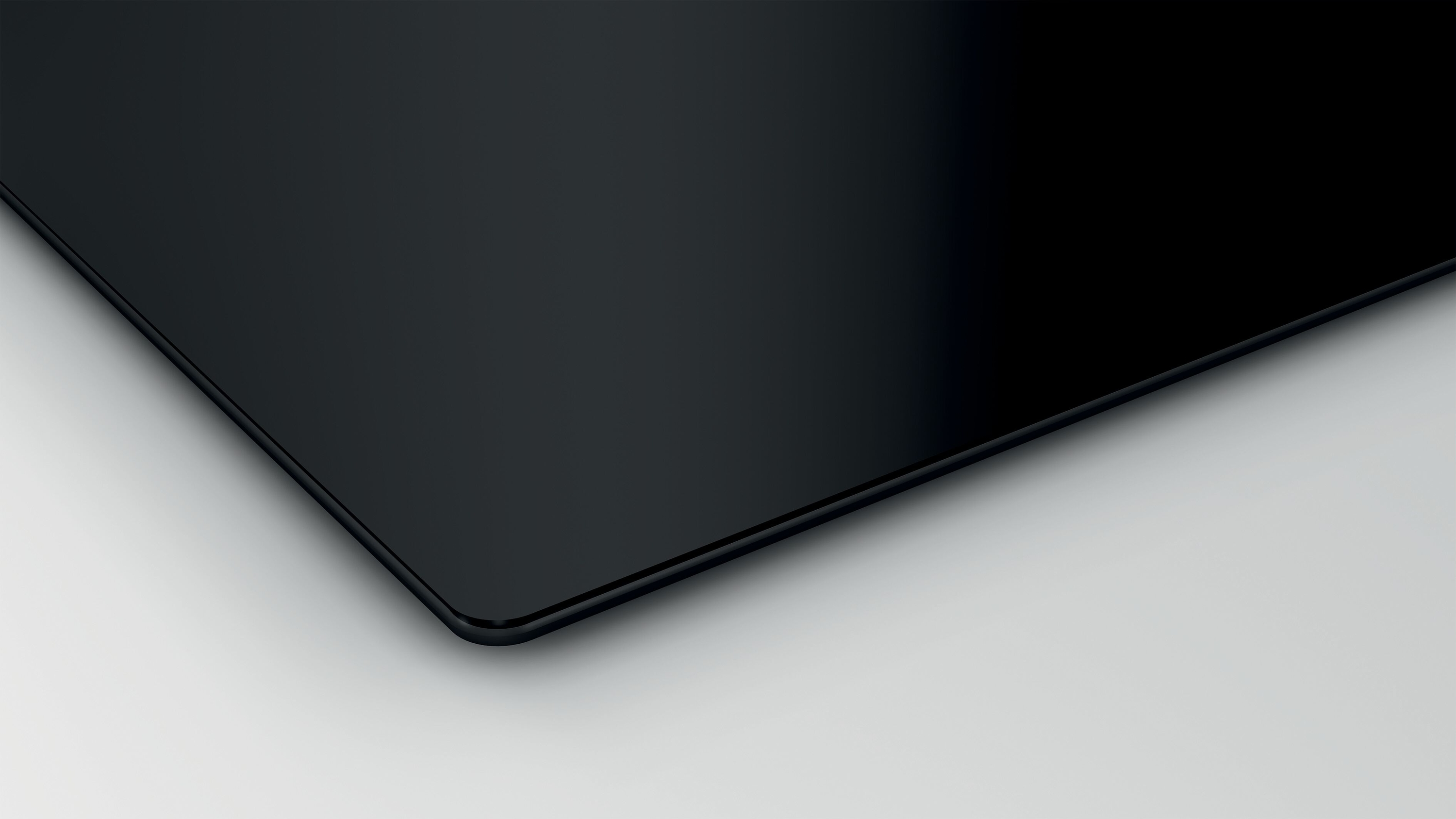 Zbliżenie czarnej płyty ceramicznej o gładkiej, odbijającej światło powierzchni.