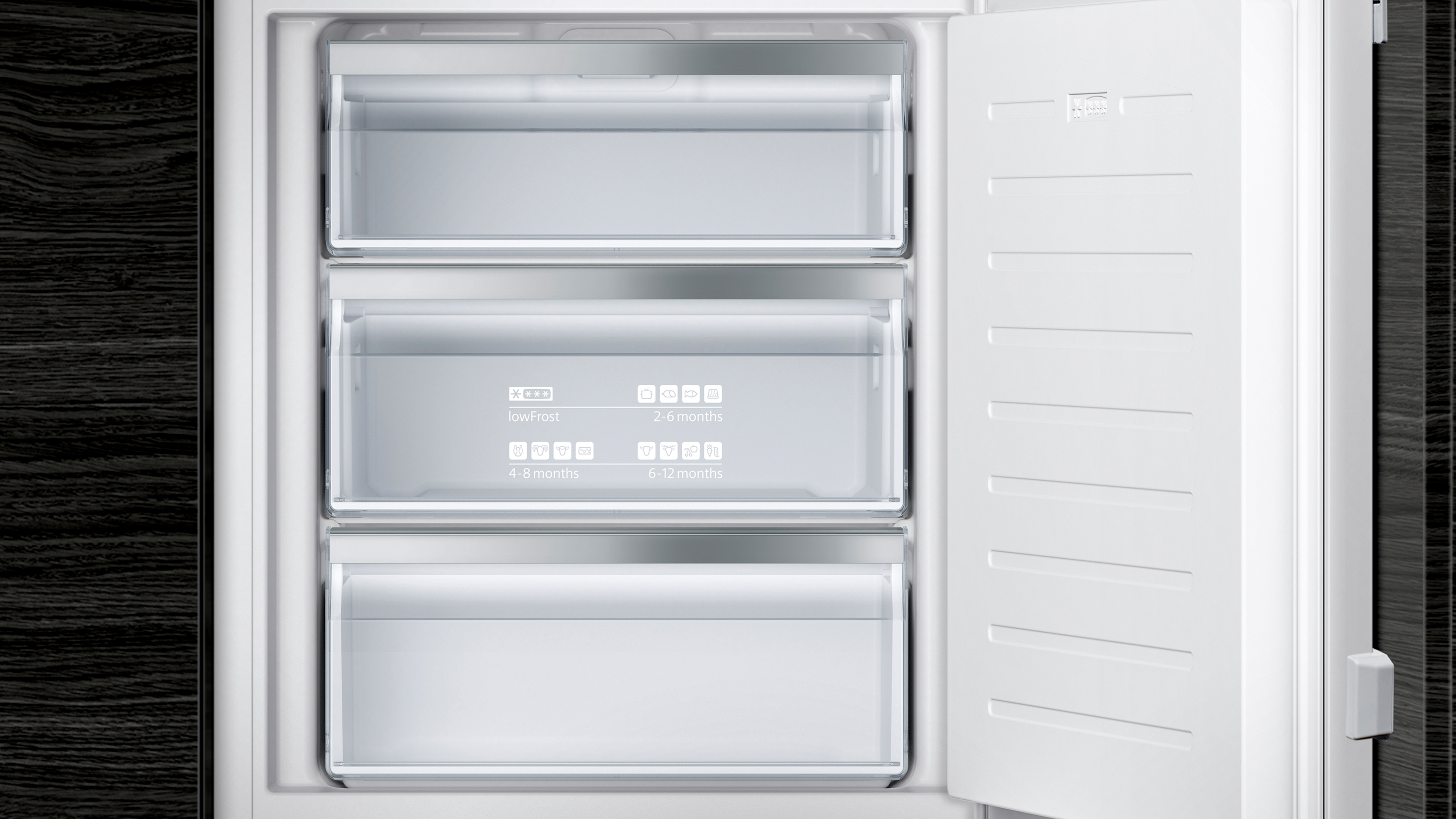 Ein offener Kühlschrank mit drei transparenten Schubladen. Die Schubladen enthalten Lebensmittel. Der Kühlschrank ist weiß.