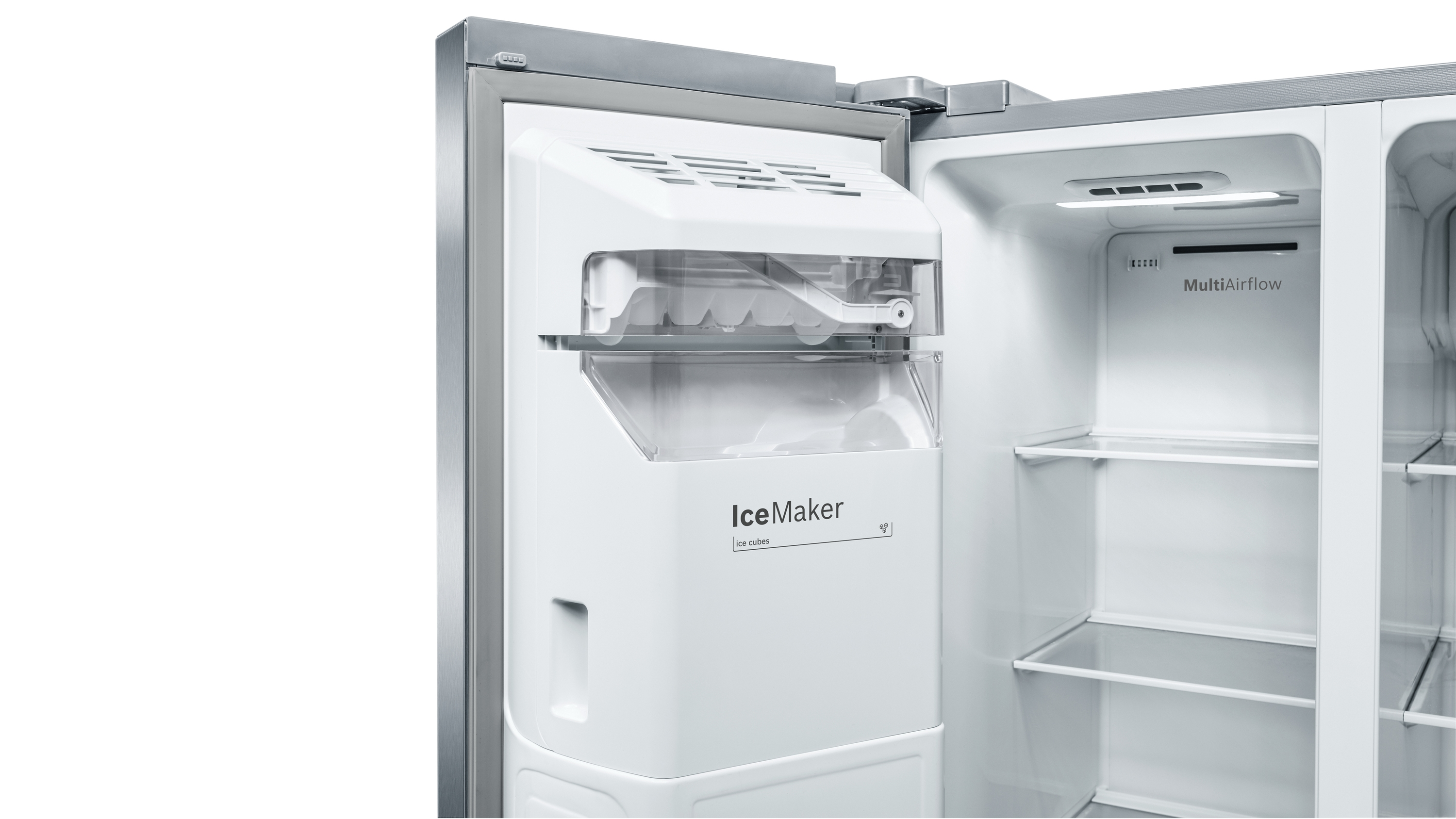 Offener Edelstahlkühlschrank. Eisbereiter und Regale sichtbar. Weißer Innenraum, weißer Hintergrund.