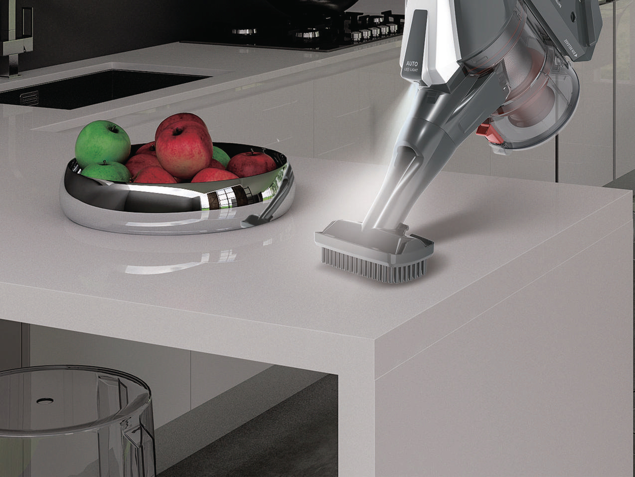 Ein Staubsauger reinigt eine weiße Oberfläche, im Hintergrund eine Obstschale.