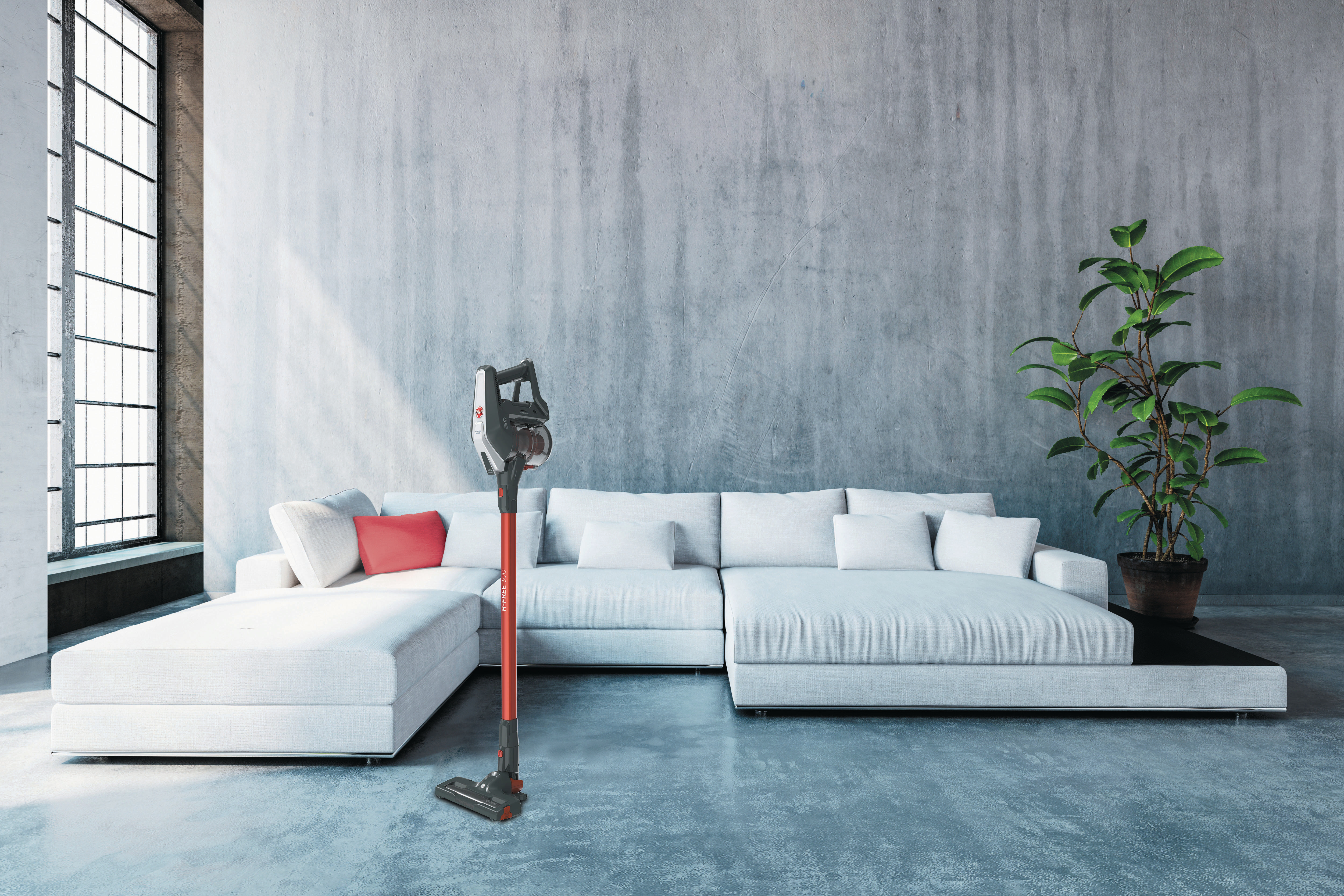 Aufrechter kabelloser Staubsauger neben Couch und Pflanze.