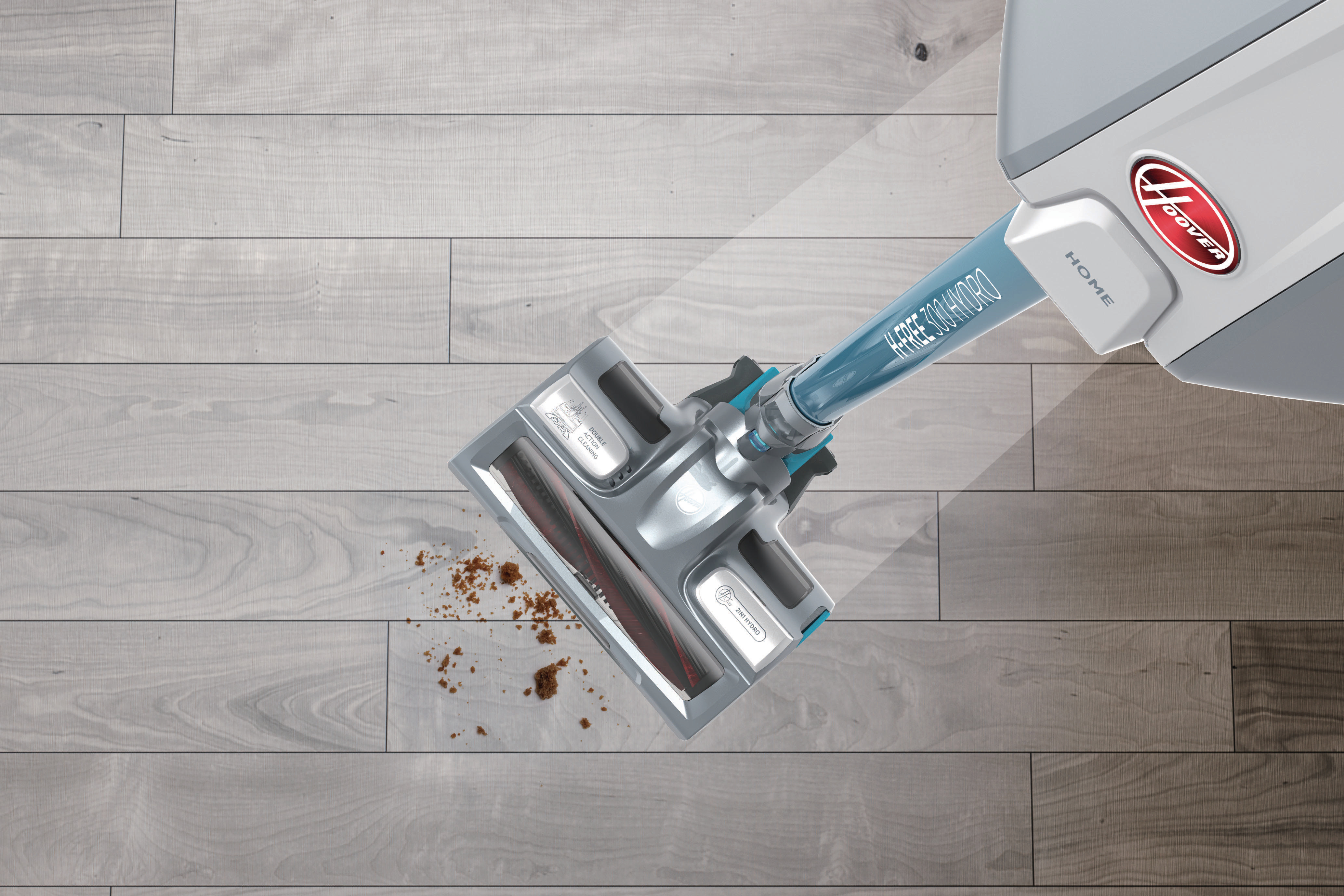 Ein Staubsauger reinigt einen Holzboden. Die Bürste hat Kontakt mit Schmutz. Die Maschine ist blau und grau.