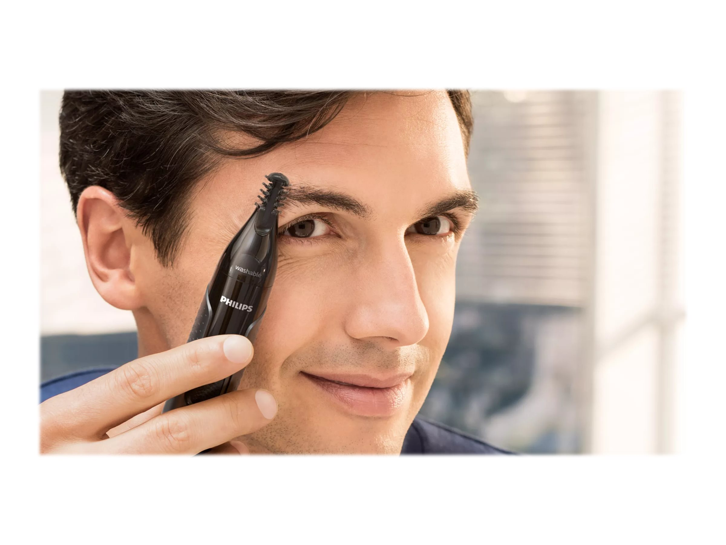 Mann trimmt seine Augenbrauen mit einem schwarzen Philips Nasenhaartrimmer.