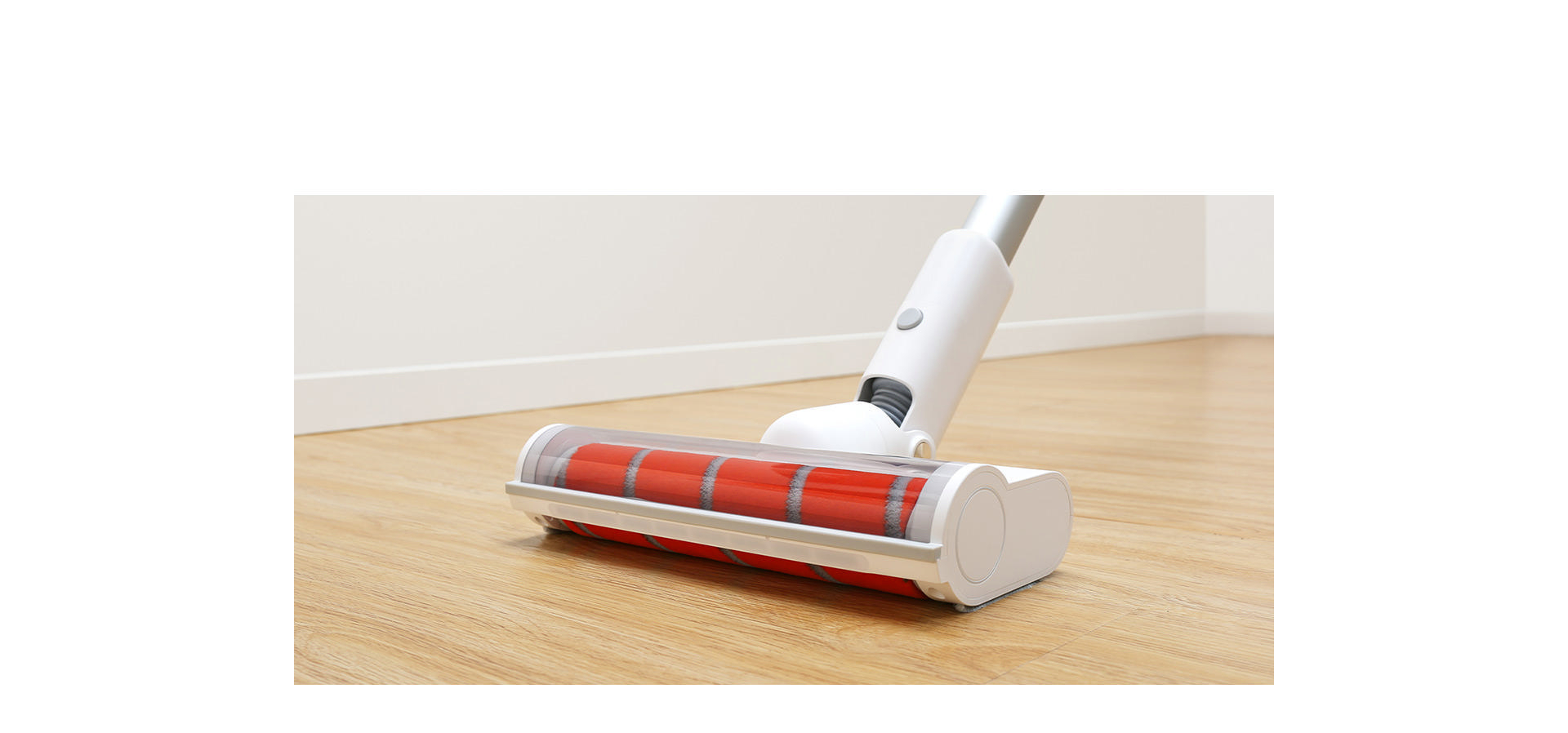 Nahaufnahme eines Staubsaugerkopfes auf hellem Holzboden mit roter Walze.