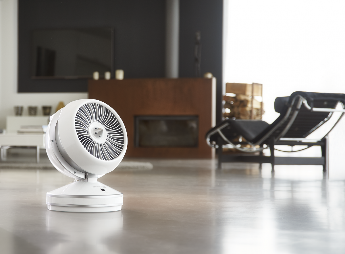 Un ventilateur blanc sans pales est posé sur un sol dans une maison moderne.