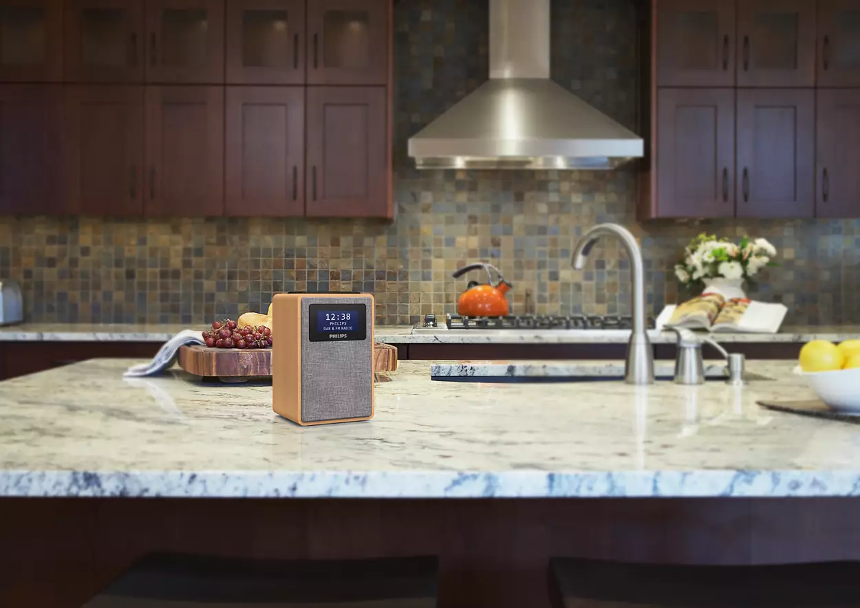 Philips radio on countertop, kitchen with wooden cabinets, a sink and kettle.