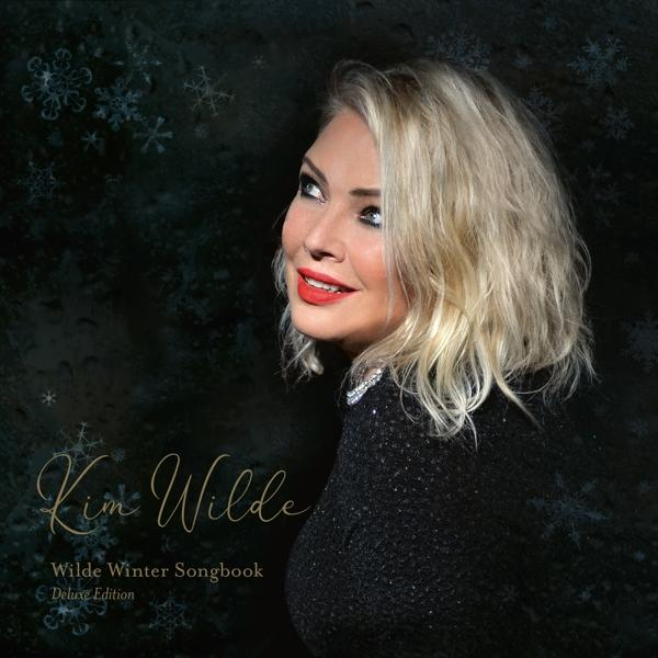 Kim Wilde blickt nach links. Sie hat blondes Haar und roten Lippenstift. Schneeflocken sind Hintergrund.