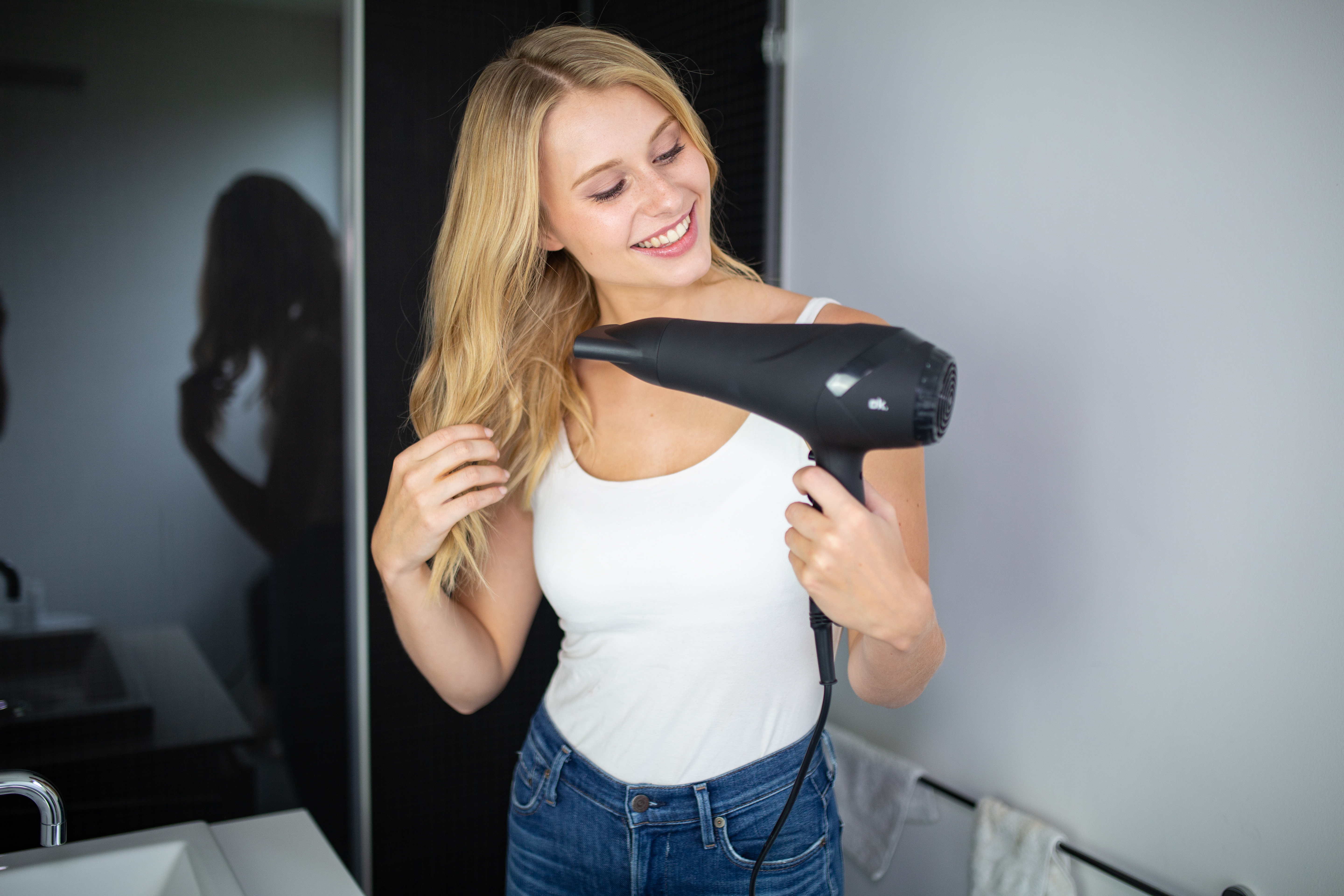 Donna in bagno che si asciuga i capelli con un asciugacapelli.