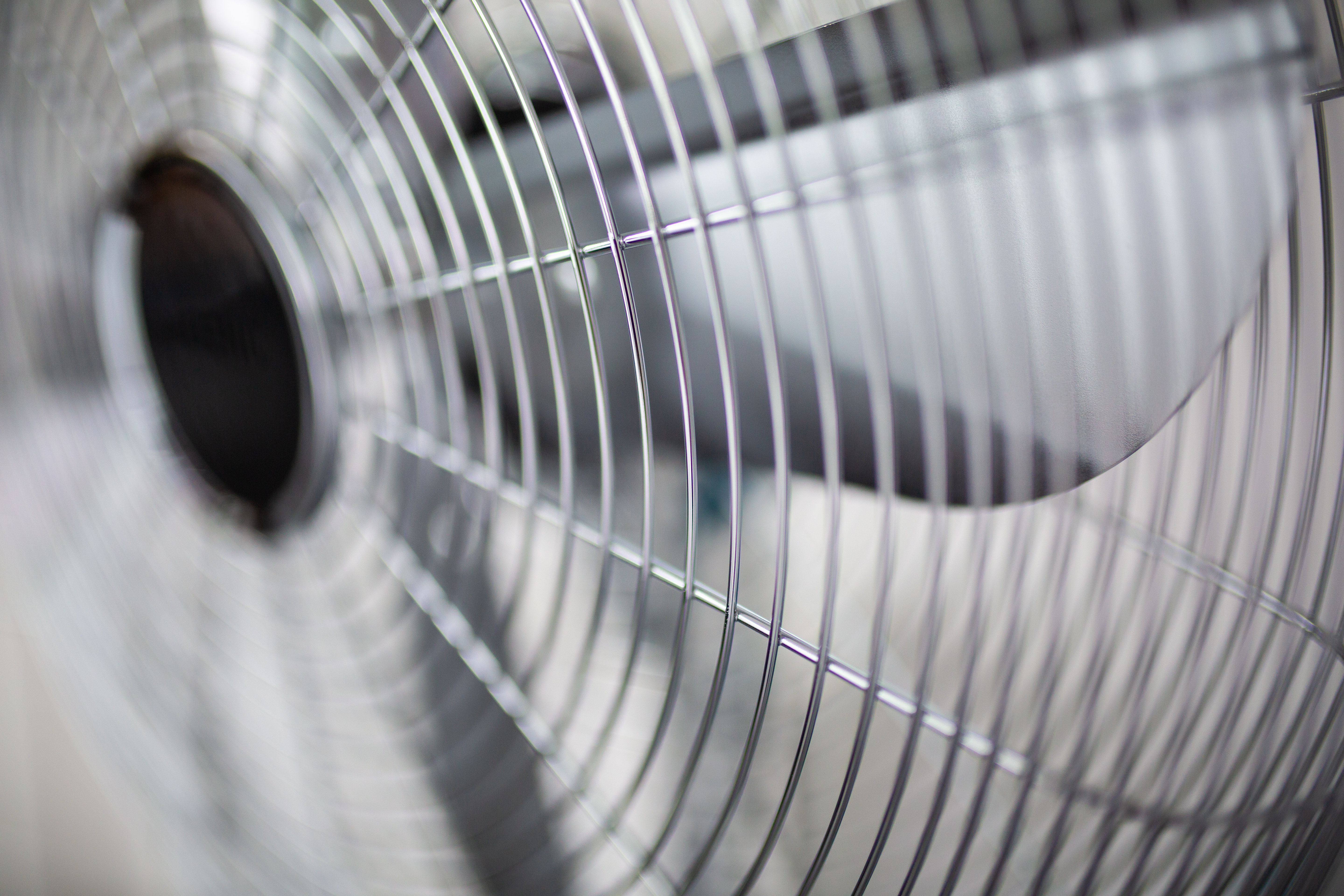 Primo piano della griglia metallica di un ventilatore con centro scuro.