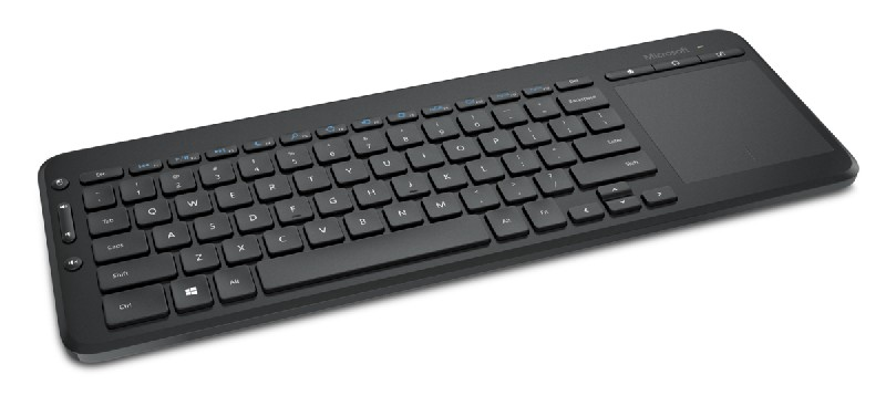 Teclado Microsoft negro con panel táctil sobre fondo blanco.