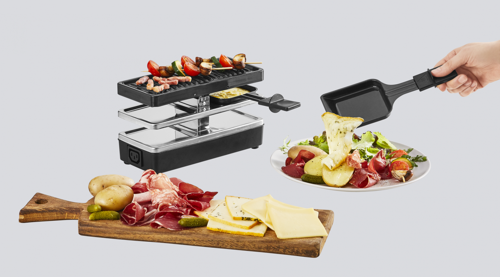 Gril à raclette avec de la nourriture. Une assiette avec de la salade, de la viande et du fromage. Planche en bois avec de la viande et du fromage.