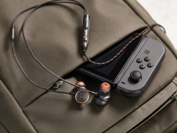 Earbuds and a gaming console controller in a backpack pocket. Black and orange color scheme.