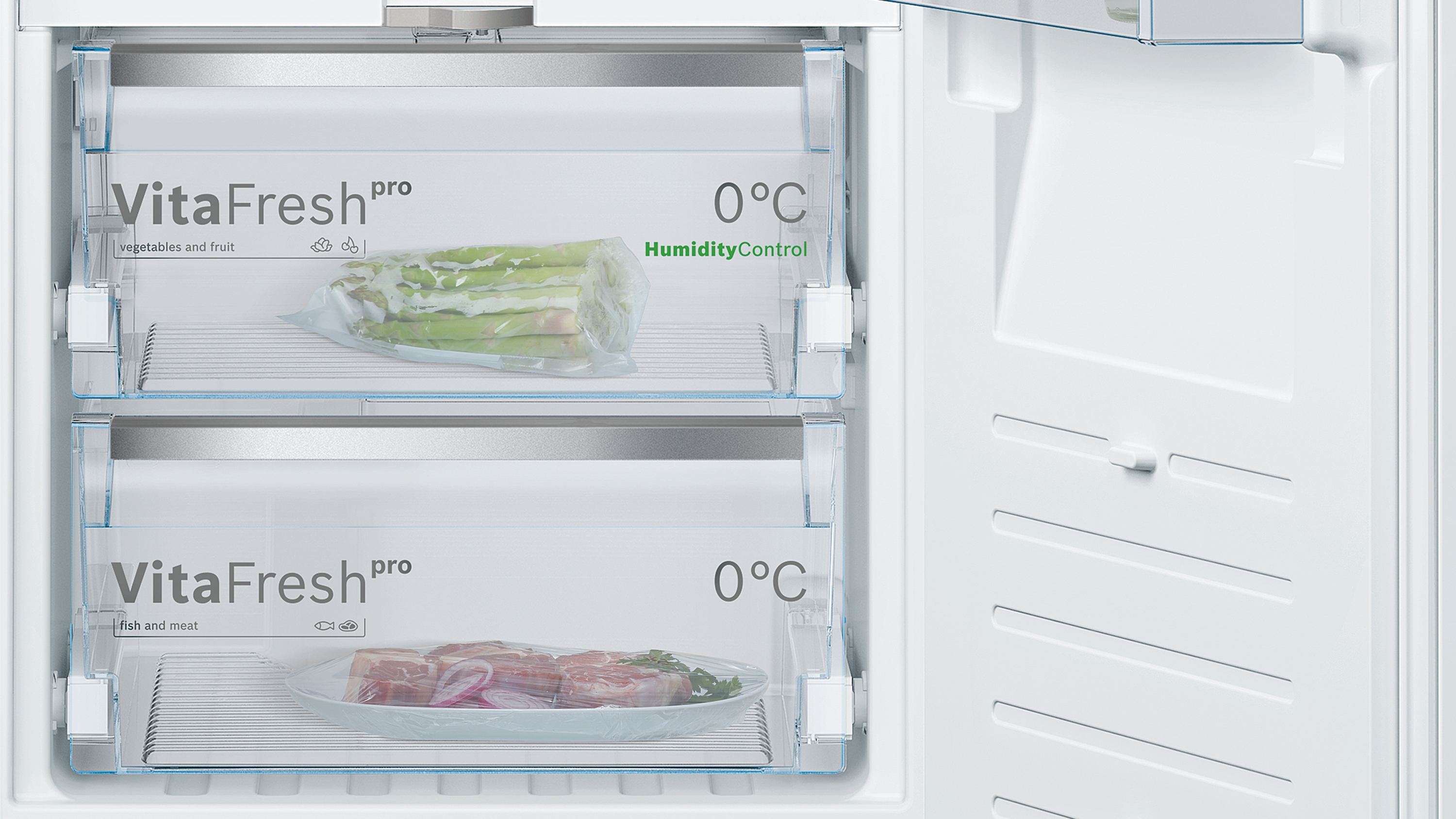 Innenraum eines Kühlschranks mit zwei Schubladen, eine mit Spargel und die andere mit Fleisch.