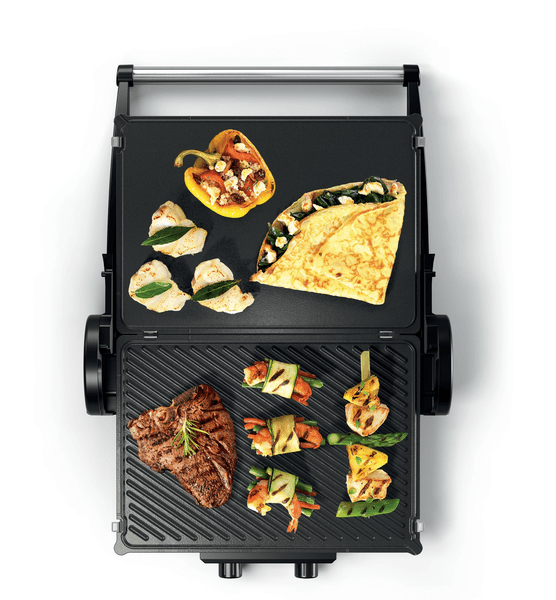 Eine Draufsicht auf einen offenen Grill mit verschiedenen gegrillten Speisen wie Steak, Paprika und Pfannkuchen.