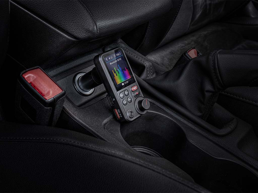 Un trasmettitore FM per auto nero all'interno di un'auto, con un display a spettro cromatico.