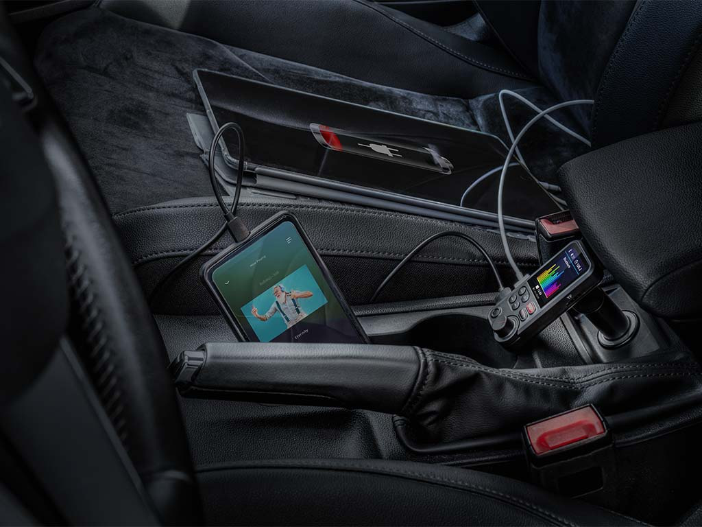 Smartphone nella console di un'auto, collegato a un lettore musicale e caricabatterie per auto.
