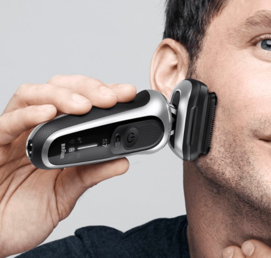 A man shaves his face with a Braun Series 7 electric shaver. Close-up.
