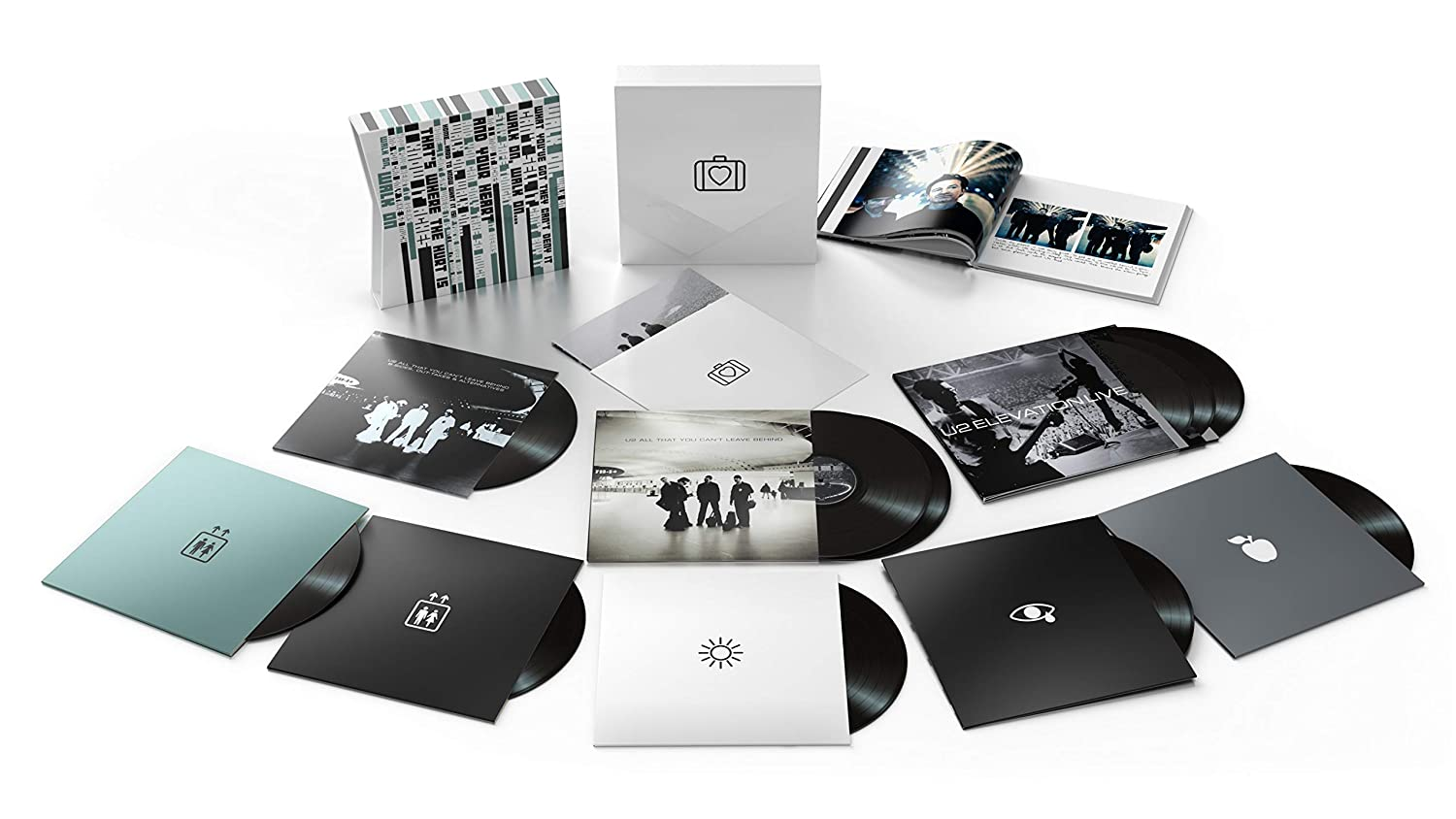 U2 albumkészlet, beleértve a bakelit lemezeket, egy könyvet és egyéb, fehér és fekete borítójú tárgyakat.